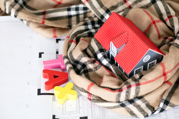 Tax word composed of small house model wrapped in scarf and English letter model