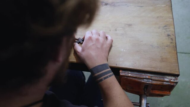 A woodcarver cuts an Orthodox ebony cross with a knife. an artisan carves a carving on a wooden cross.