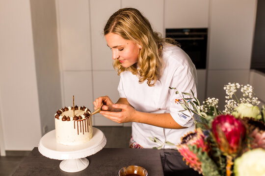 Frau backt eine Torte in der K&uuml;che mit Schokodrip