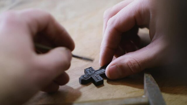 A woodcarver cuts an Orthodox ebony cross. an artisan carves a carving on a wooden cross.
