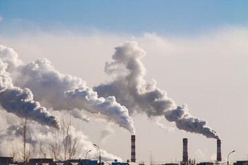 Fototapeta na wymiar industrial chimneys with heavy smoke causing air pollution on the blue sky background