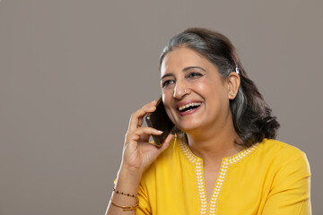 A SENIOR ADULT WOMAN HAPPILY TALKING ON PHONE	