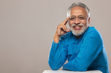 A SENIOR ADULT MAN SITTING AND POSING IN FRONT OF CAMERA	