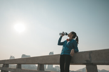 woman athlete takes a break. she drinking water after running.