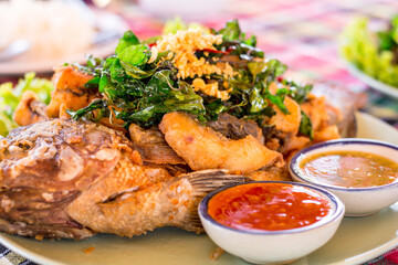 Deep fried fish with Thai herb on plate with hot and sour dipping sauce.