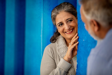 AN ADULT WOMAN LOVINGLY LOOKING AT HUSBAND WHILE STANDING BEHIND A WALL	