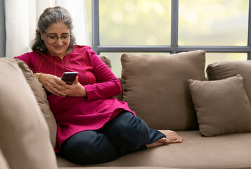 A SENIOR ADULT WOMAN HAPPILY USING MOBILE PHONE	