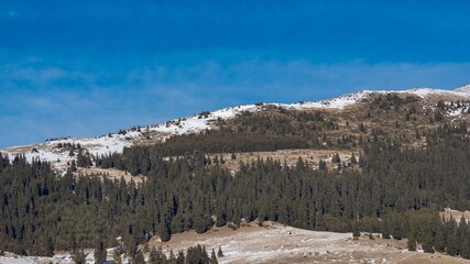 Beautiful winter panoramic natural mountain landscape. Attractive snowy peaks of Rila Mountains, Bulgaria. White clouds in dynamic blue sky, perfect conditions for tourism recreation and winter sports