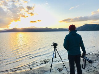 カメラマンの男性　夕焼け　湖のほとり