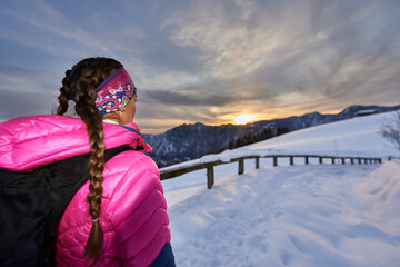 Fototapeta na wymiar Girl watches the sunset in the mountains during a hike