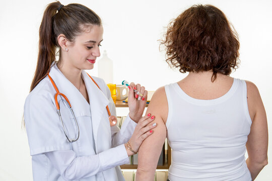 Doctor female giving Covid vaccine to senior woman intramuscular injection in female arm