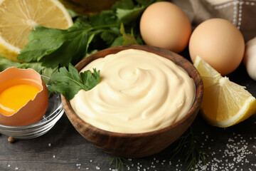 Wooden bowl of mayonnaise and ingredients for cooking, close up