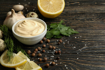 Bowl with mayonnaise and ingredients for cooking on wooden background