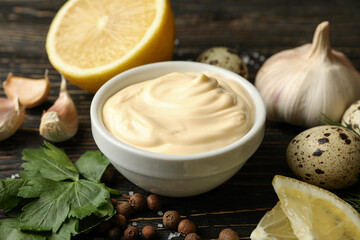 Bowl with mayonnaise and ingredients for cooking on wooden background