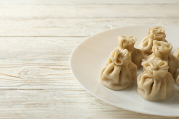 Plate with tasty khinkali on wooden background