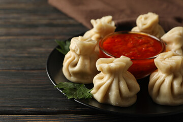 Concept of tasty lunch with plate of khinkali and sauce on wooden background