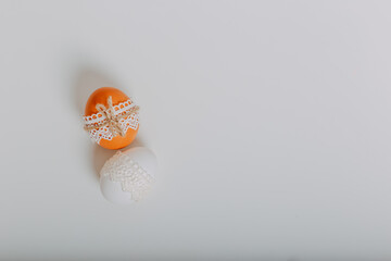 Two easter eggs on white background. Easter eggs with lace border around. Process of decorating easter eggs with lace and rope.