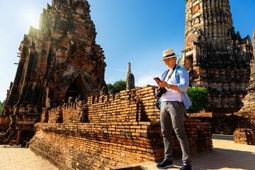 Travelers traveling to Asia. Foreign tourists traveling in the old city of Ayutthaya, Thailand. Young man visiting Ayutthaya attractions and landmarks in Thailand. - obrazy, fototapety, plakaty