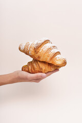The woman hand has hold croissants and the beige background 