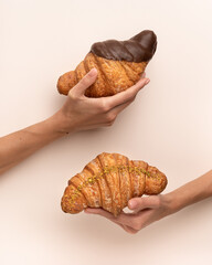 The woman hand has hold croissants and the beige background 