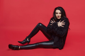 attractive brunette with long hair sitting in the Studio on a red background