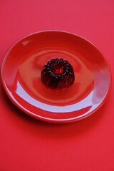 Red jelly dessert in a red round plate on a bright red background . A gelatinous dietary low calorie vegetarian dessert. Vegan dessert. Low Calorie  Sweets