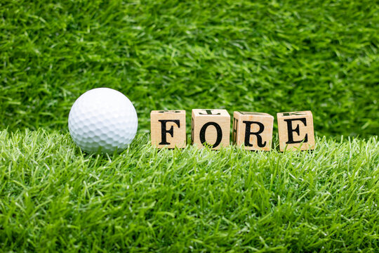 Golf FORE with golf ball and wooden alphabet on green grass background