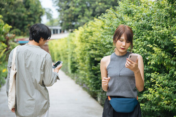 Asian thai woman jogging at park and looking at music playlist on smartphone.