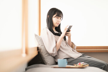 自宅でスマートフォンを操作する女性