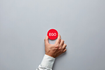 Businessman hand holding a red badge with the word ego.