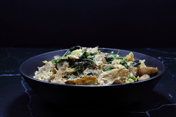 Fried and stirred spicy fresh vermicelli with tofu sheet, chilly and basil serving on the plate. Famous vegetarian menu in Asia restaurant. 