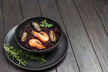Shrimp and mussels with black rice in bowl.