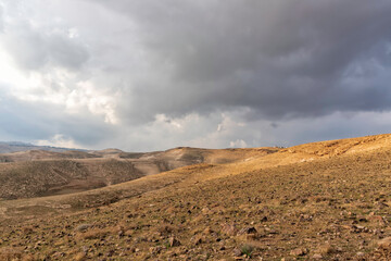 Fototapeta na wymiar View of the rocky hills of the Judean Desert under a stormy sky. Landscape