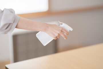 スプレーで部屋を消毒・殺菌する女性