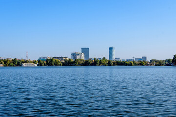 Naklejka premium Landscape with many large green and old trees near the lake in a sunny autumn day in Herastrau Park in Bucharest, Romania .