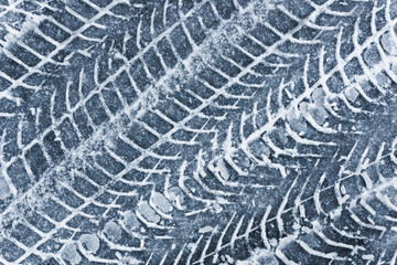 Snow tyre mark. Asphalt covered in snow. Dangerous road conditions. Car imprint on frozen ground. Tire trail on ice.