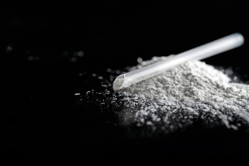 ketamine drugs and plastic straw on black wood background.Drug epidemic concept