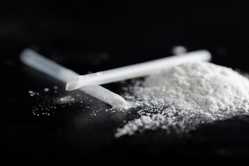 ketamine drugs and plastic straw on black wood background.Drug epidemic concept