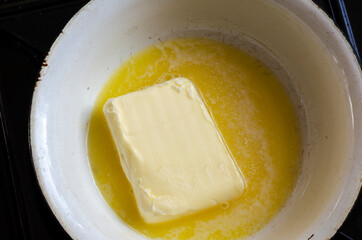 Melt the butter in a white metal bowl on the kitchen stove.