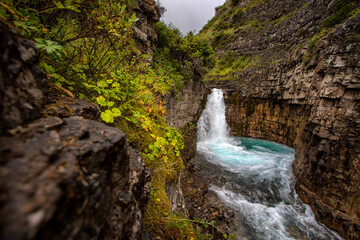 Fototapeta na wymiar waterfall among green rocks