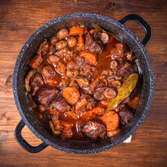 Ready burgundy beef in a saucepan on a wooden table close-up - top view