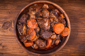 Ready burgundy beef in a clay bowl on a wooden table close up
