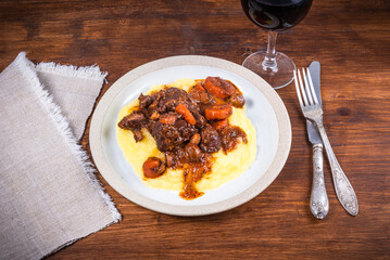 Burgundy beef with mashed potatoes in a plate and a glass of red wine on a wooden table close-up, top view