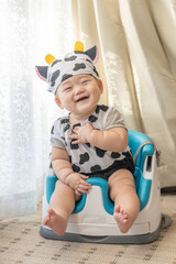 Fototapeta premium リビングの窓辺で牛のコスプレをしてお座りをする赤ちゃん
