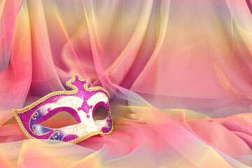 Photo of elegant and delicate purple Venetian mask over colorful chiffon background