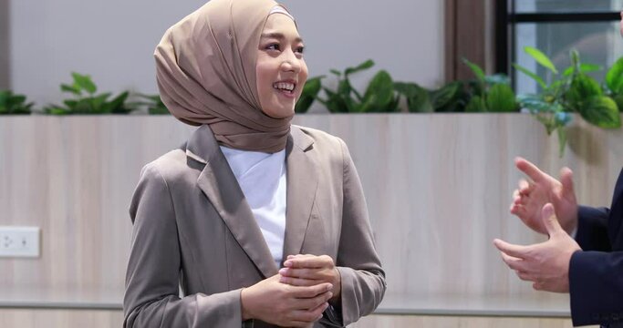 Young business muslim woman and business man colleague walking and discussing outside the office. Woman is holding a coffee and businessman is holding a digital tablet outdoor.