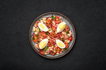 A Piyaz salad on black plate on dark slate table top. Turkish cuisine vegetarian dish. Middle eastern cuisine food. Top view