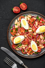 A Piyaz salad on black plate on dark slate table top. Turkish cuisine vegetarian dish. Middle eastern cuisine food. Top view