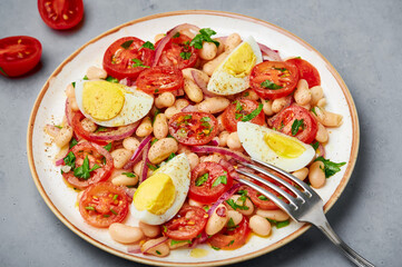 A Piyaz salad on white plate on gray concrete table top. Turkish cuisine vegetarian dish. Middle eastern cuisine food. Close up