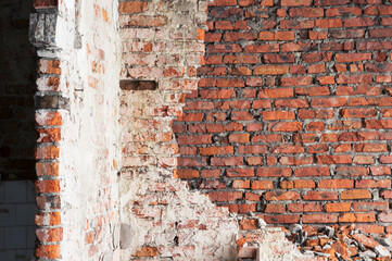 An old red brick wall with remnants of white plaster. Vintage background
